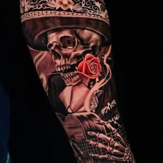 a man with a skull tattoo on his arm holding a red rose and playing the guitar