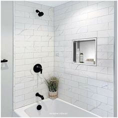 a bathroom with white tile and black faucet handles on the shower head is shown