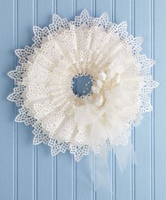 a white doily wreath hanging on a blue wall