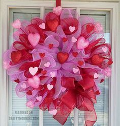 a pink wreath with hearts hanging from it's front door on a window sill