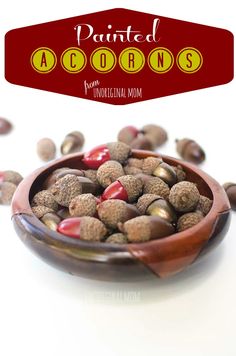 a bowl filled with nuts sitting on top of a white table next to a red sign that says painted acorns