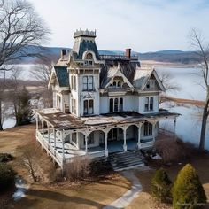 an old victorian style house sits next to the water