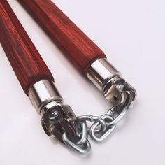 two wooden handles with chains attached to them on a white surface, one is red and the other is silver