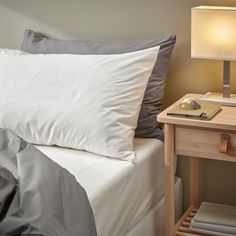 a bed with two pillows and a lamp on the side table next to it in a bedroom