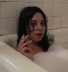 a woman sitting in a bathtub with bubbles on it