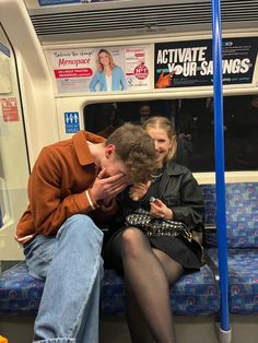 a man and woman sitting on a subway train