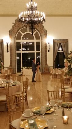 a bride and groom standing in the middle of a room with tables set for their wedding reception