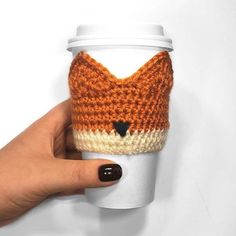 a hand holding a coffee cup cozyie with a fox face on the front and side