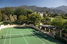 an aerial view of a tennis court with mountains in the background