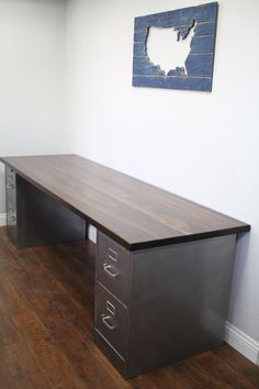 an office desk with two file cabinets in the corner and a painting on the wall