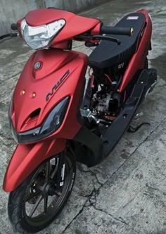 a red motorcycle parked next to a cement wall