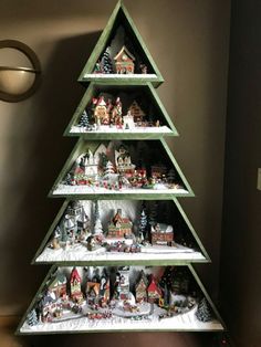 a christmas tree made out of wooden shelves filled with small houses and snow covered trees