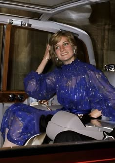 a woman sitting in the back seat of a car wearing a blue dress and heels