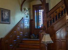 the stairs in this house are made of wood and have intricate carvings on them, along with a lamp