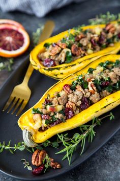 two delicacy squash boats on a black plate with garnish and pecans