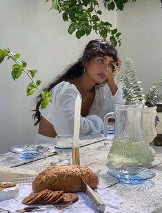 a woman sitting at a table with bread and water