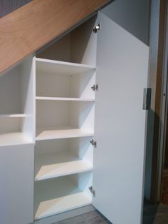 an open closet under the stairs in a room with wood flooring and white walls