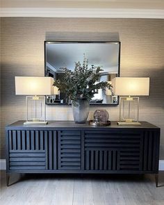 a vase with flowers on top of a table next to a mirror and lamp shades