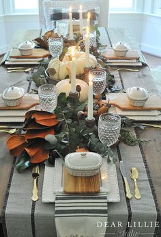 a table set with candles, plates and silverware