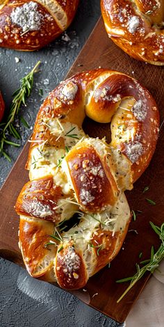 some breads with cheese and herbs on a wooden cutting board next to other baked goods