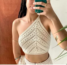 a woman taking a selfie in front of a mirror while wearing a crop top