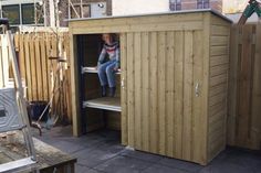 a woman sitting on top of a wooden shed