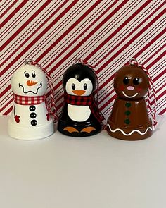 three snowmen and a penguin are standing next to each other in front of a striped wall