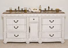 a white bathroom vanity with two sinks and marble counter top, in front of a wall