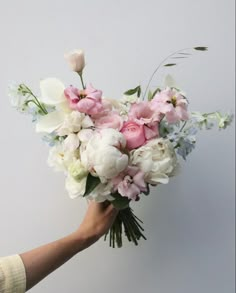 a person holding a bouquet of white and pink flowers