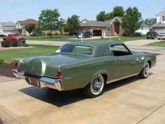 an old green car is parked in the driveway