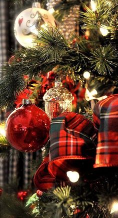 the christmas tree is decorated with red and black plaid ribbon, silver ornament ornaments, and pine cones