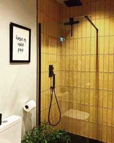 a bathroom with a toilet, shower and plant in it