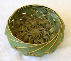 a close up of a basket made out of leaves on a white tablecloth background