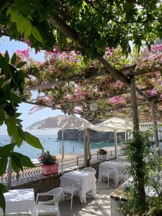 an outdoor dining area with tables and umbrellas on the beach in front of water