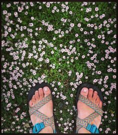 a person wearing sandals standing in front of flowers