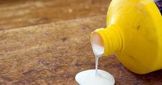 a yellow bottle is being poured into a white cup