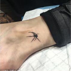 a small black spider tattoo on the left side of the ankle, with an arrow in the center