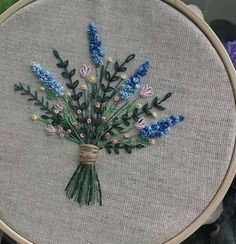 a close up of a embroidery on a piece of cloth with blue and pink flowers