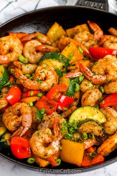 shrimp and vegetable stir fry in a skillet on a marble counter top, ready to be eaten