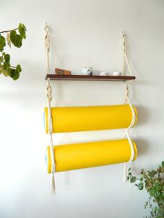 two yellow tubes hanging from a wall next to a potted plant on a shelf