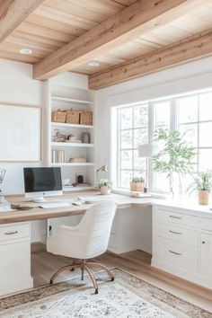 a home office with white walls and wooden ceilinging, built in shelving units