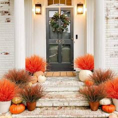 front porch decorated for fall with pumpkins and gourds on the steps to the door