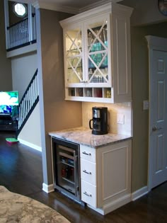 a kitchen area with white cabinets and marble counter tops, along with stairs leading up to the second floor