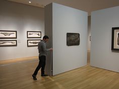 a woman looking at artwork on display in an art gallery with white walls and wooden floors