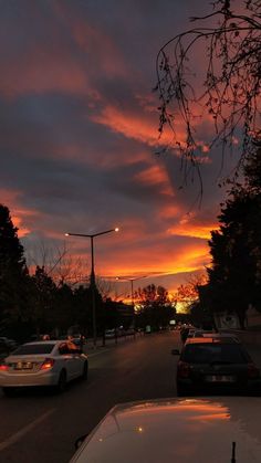 cars are parked on the street as the sun sets