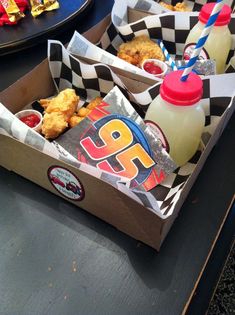 two boxes filled with food sitting on top of a table next to drinks and condiments