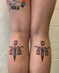 two women with tattoos on their legs, one has flowers and the other has leaves