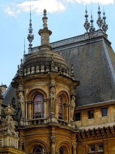 an old building with a clock on the top of it's roof and windows