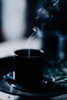 a black cup with steam rising from it