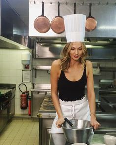 a woman in a kitchen preparing food with pots and pans on the stove top